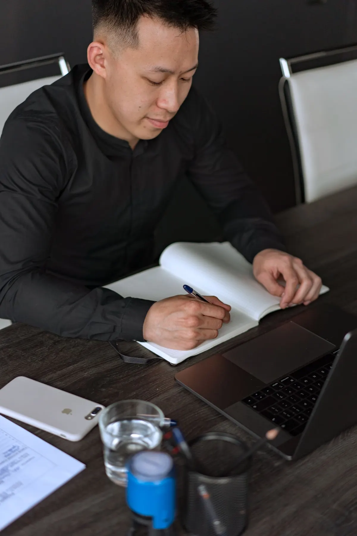 Người đàn ông ghi chép vào sổ tay bên máy tính